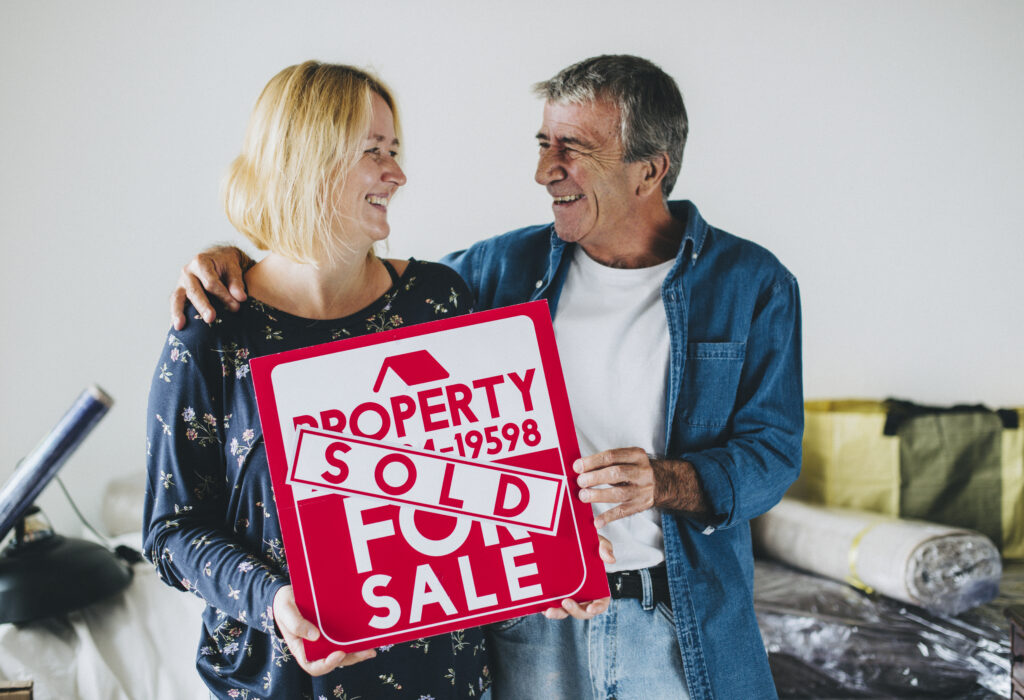Couple with a property for sale sign